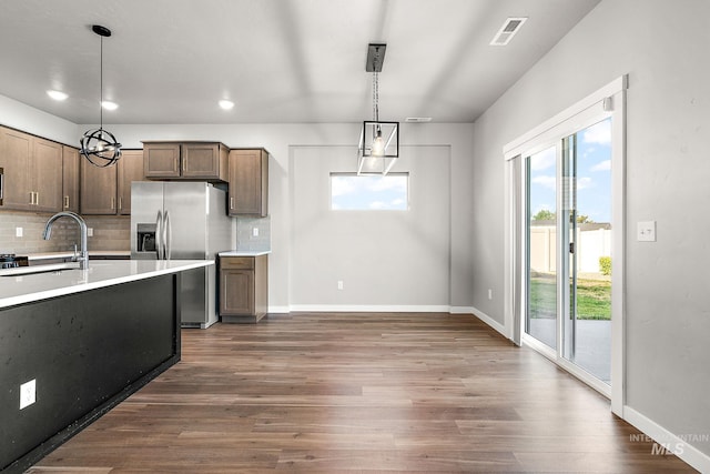 1755 N Crystal Cove Ave, Meridian, ID 83646 - kitchen with stainless steel refrigerator with ice dispenser, light countertops, backsplash, dark wood-type flooring, and decorative light fixtures