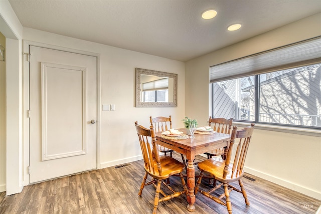 dining space with baseboards, visible vents, and wood finished floors