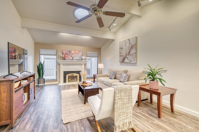 living area with a tile fireplace, baseboards, beam ceiling, and wood finished floors