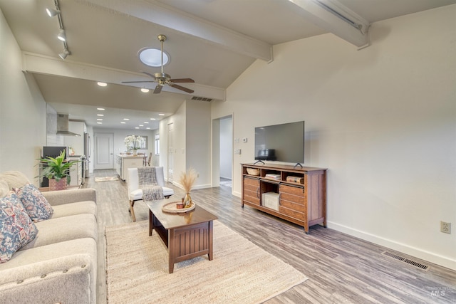 living room featuring a ceiling fan, visible vents, lofted ceiling with beams, and wood finished floors