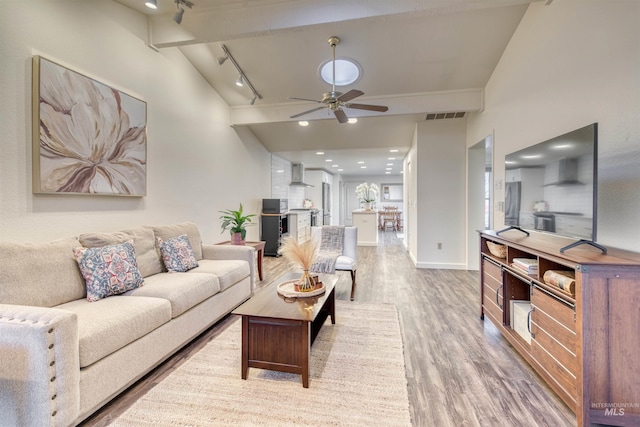 living room with wood finished floors, a ceiling fan, visible vents, beam ceiling, and rail lighting