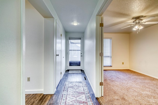 hall with a textured ceiling, wood finished floors, and baseboards