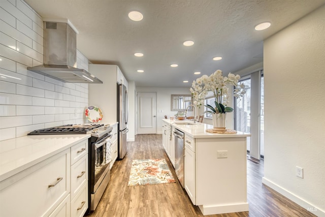 kitchen with wall chimney exhaust hood, appliances with stainless steel finishes, light wood-style flooring, and decorative backsplash