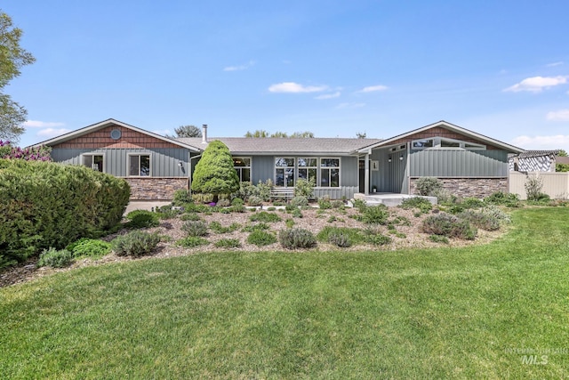 view of front of property featuring stone siding, a front lawn, and board and batten siding