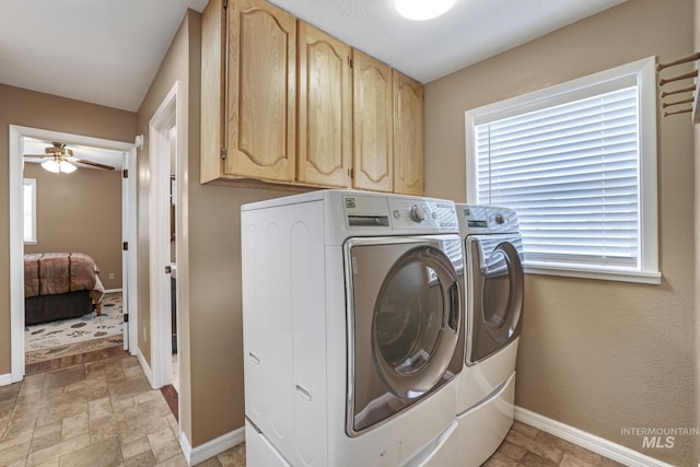 washroom with washing machine and clothes dryer, cabinet space, a ceiling fan, stone finish floors, and baseboards