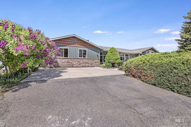 ranch-style home with stone siding and board and batten siding