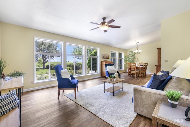 living area featuring a chandelier, a ceiling fan, wood finished floors, and baseboards