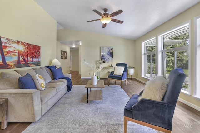 living room with lofted ceiling, wood finished floors, a ceiling fan, and baseboards