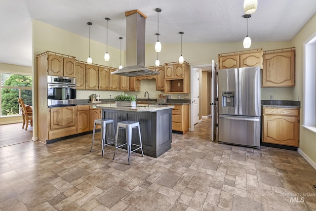 kitchen featuring stainless steel appliances, island exhaust hood, a sink, stone tile floors, and a center island