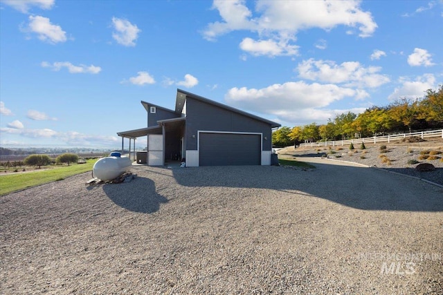 view of home's exterior with a garage and a rural view