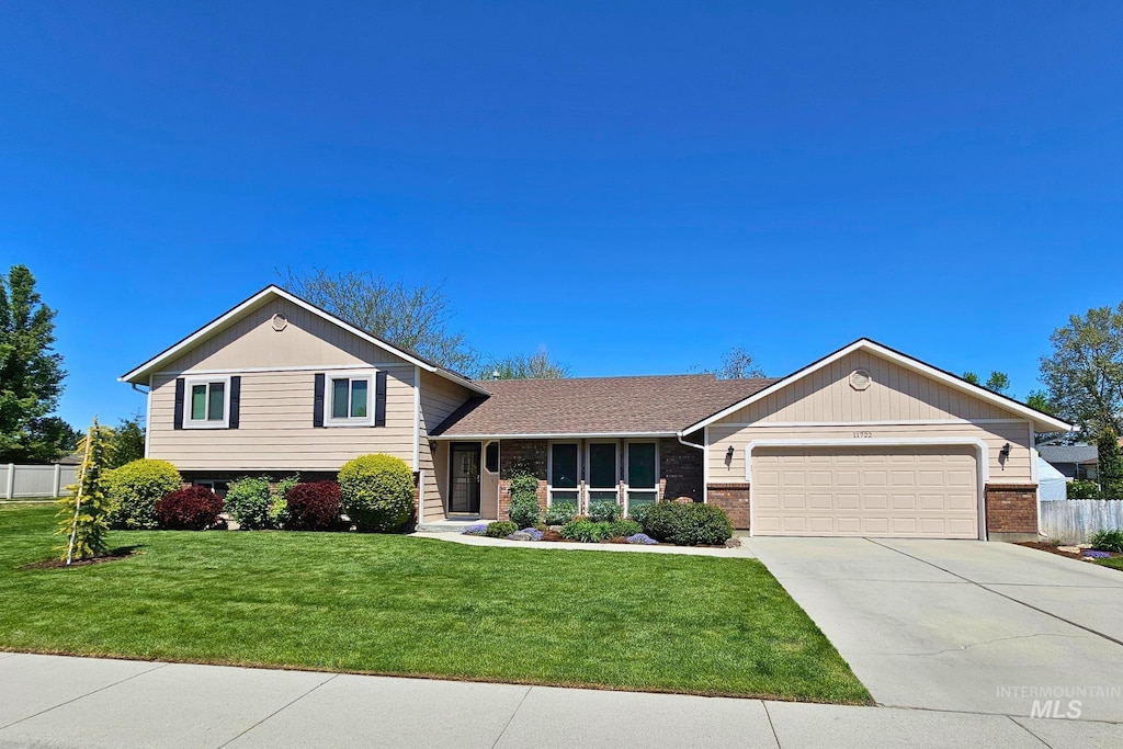 tri-level home with a garage, concrete driveway, and brick siding
