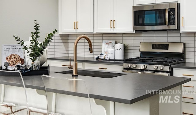 546 Thistle Hills Ave, Middleton, ID 83644 - kitchen featuring tasteful backsplash, white cabinets, a sink, dark countertops, and appliances with stainless steel finishes