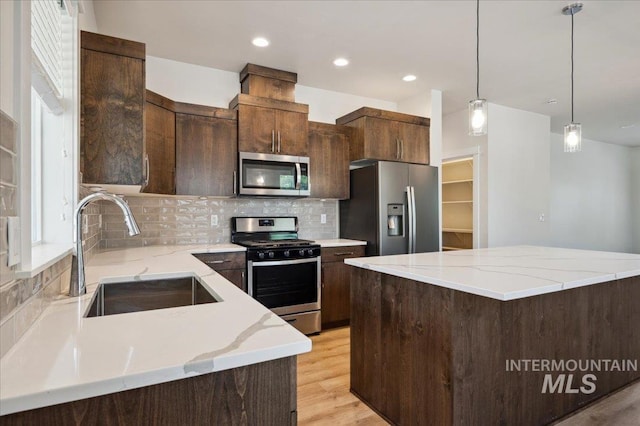 10276 W Utahna Rd, Boise, ID 83714 - kitchen featuring appliances with stainless steel finishes, a sink, backsplash, light wood-style floors, and light stone countertops