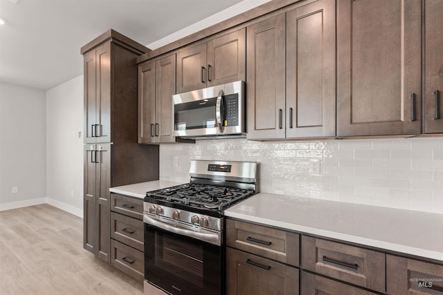 202 S Koyukuk Ln, Star, ID 83669 - kitchen with stainless steel appliances, baseboards, light wood-type flooring, and decorative backsplash