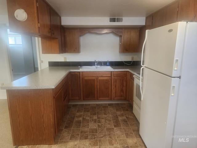 855 N 9th E, Mountain Home, ID 83647 - kitchen featuring freestanding refrigerator, a sink, brown cabinets, a peninsula, and light countertops