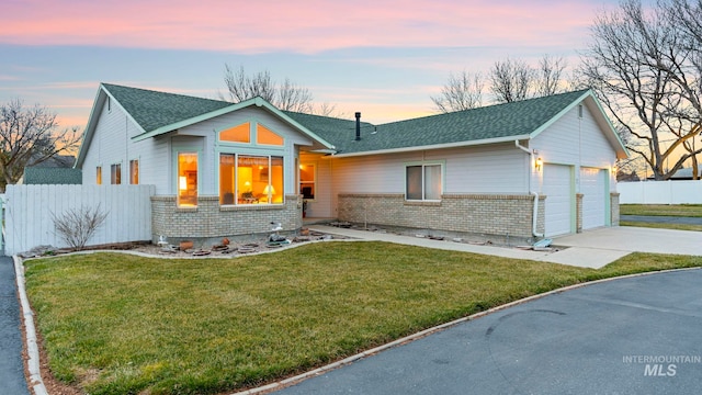 view of front of home featuring a front lawn, fence, brick siding, and a shingled roof