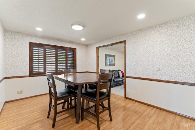dining area featuring wallpapered walls, baseboards, and light wood-style floors