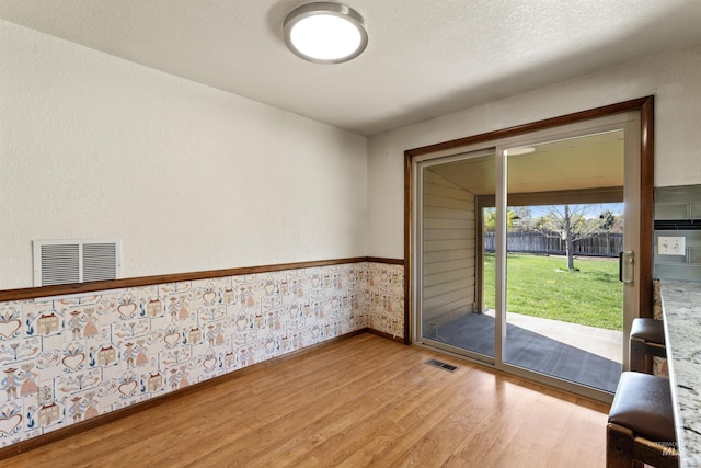 doorway with light wood-type flooring, baseboards, and visible vents