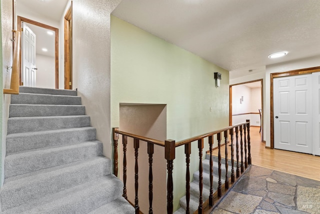 stairs with wood finished floors and recessed lighting