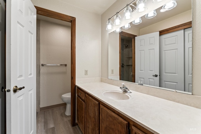 full bathroom with baseboards, wood finished floors, toilet, and vanity