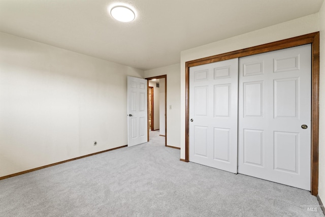unfurnished bedroom with a closet, baseboards, and light carpet