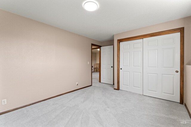 unfurnished bedroom featuring a closet, baseboards, and light carpet