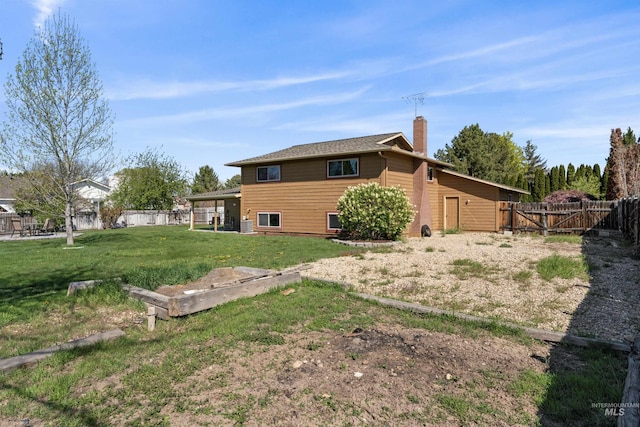 rear view of house featuring a chimney, a gate, a fenced backyard, and a lawn