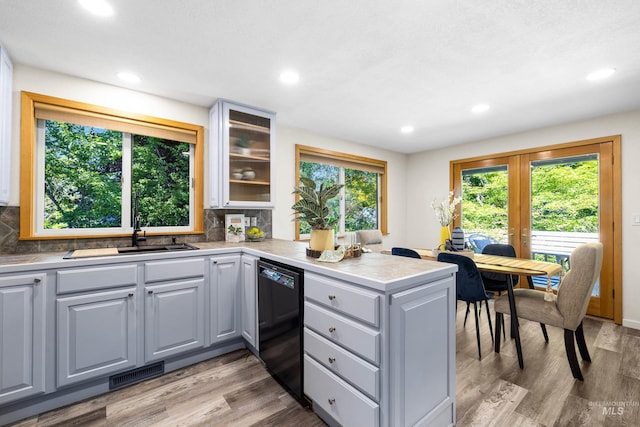 4130 S Ticonderoga Way, Boise, ID 83706 - kitchen featuring dishwasher, a peninsula, a sink, tasteful backsplash, and glass insert cabinets