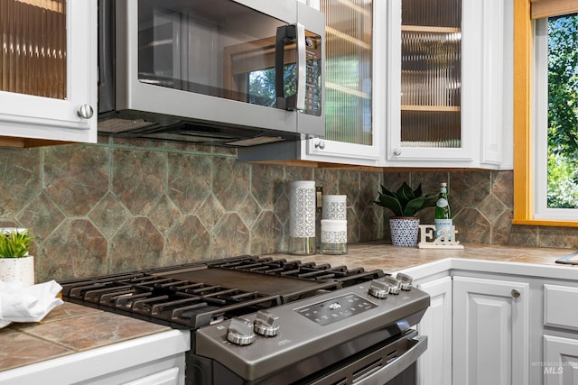 4130 S Ticonderoga Way, Boise, ID 83706 - kitchen with stainless steel appliances, white cabinetry, glass insert cabinets, and tile countertops