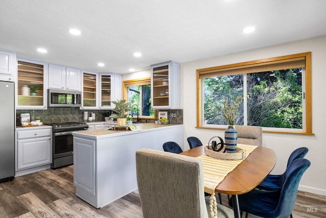 4130 S Ticonderoga Way, Boise, ID 83706 - kitchen featuring appliances with stainless steel finishes, a peninsula, decorative backsplash, wood finished floors, and recessed lighting