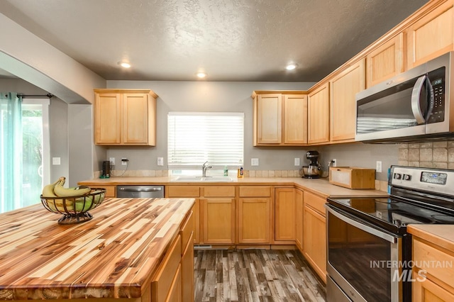 kitchen with butcher block countertops, plenty of natural light, stainless steel appliances, and sink