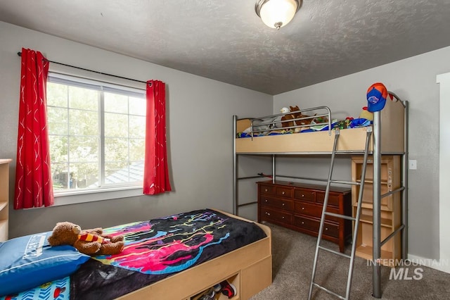 bedroom with dark colored carpet and a textured ceiling