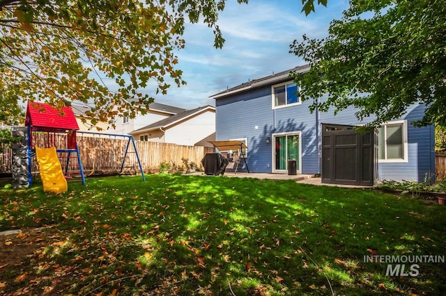 rear view of property with a lawn, a playground, and a patio