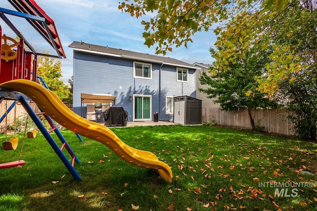 rear view of property with a playground, a yard, and a shed