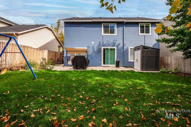 back of house featuring a lawn, a storage shed, a playground, and a patio