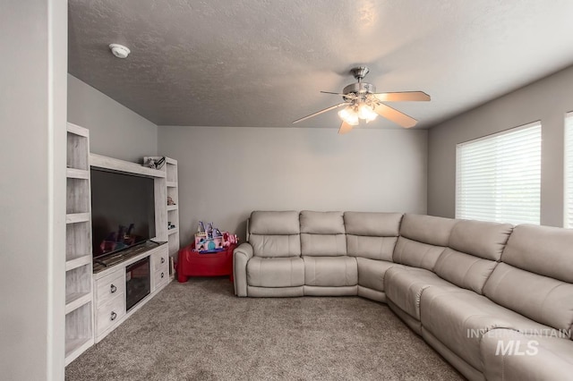 carpeted living room featuring ceiling fan and a textured ceiling