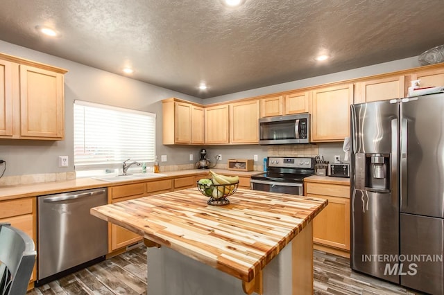 kitchen with appliances with stainless steel finishes, dark hardwood / wood-style flooring, a textured ceiling, sink, and butcher block counters