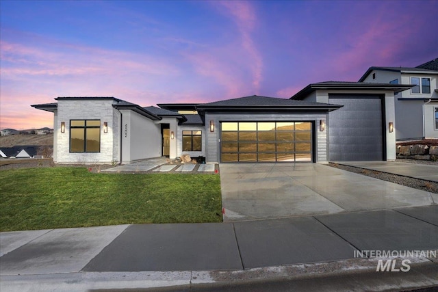 view of front of home featuring a garage, stone siding, driveway, and a yard