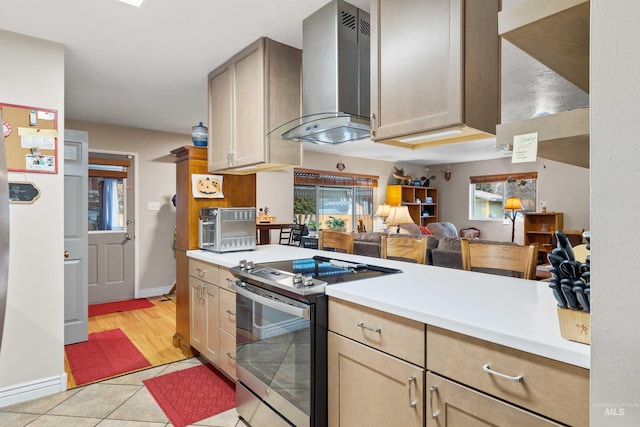 kitchen with a toaster, stainless steel electric range oven, light tile patterned floors, light countertops, and wall chimney range hood