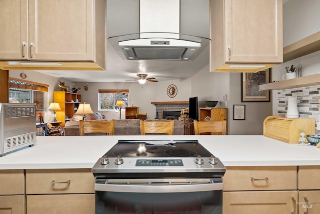 kitchen with open floor plan, island exhaust hood, stainless steel electric stove, light countertops, and a fireplace