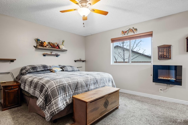 carpeted bedroom with a ceiling fan, baseboards, a textured ceiling, and a glass covered fireplace