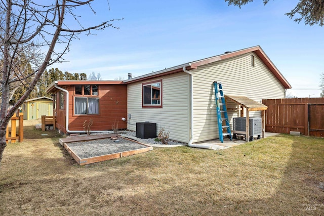 back of house with central AC unit, a storage shed, an outdoor structure, fence, and a lawn