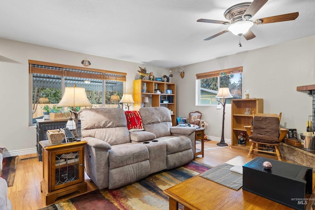 living area featuring a ceiling fan, baseboards, and wood finished floors