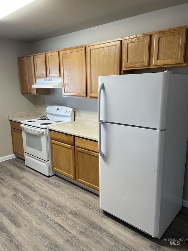 255 Elm, Vale, OR 97918 - kitchen with white appliances, under cabinet range hood, light wood finished floors, light countertops, and brown cabinets