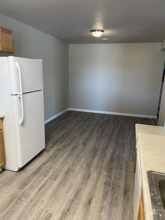 255 Elm, Vale, OR 97918 - kitchen with freestanding refrigerator, dark wood-style flooring, brown cabinetry, and baseboards