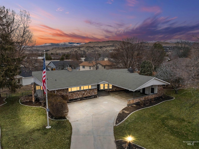 view of front of house featuring a yard, roof with shingles, concrete driveway, and a mountain view