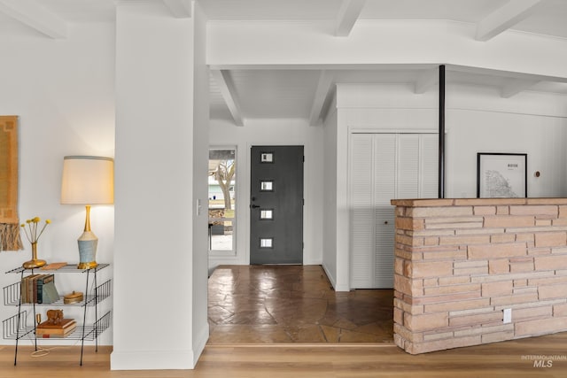 entrance foyer with baseboards, wood finished floors, and beam ceiling