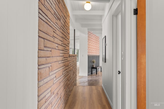 hallway featuring wood finished floors, beam ceiling, and wooden walls