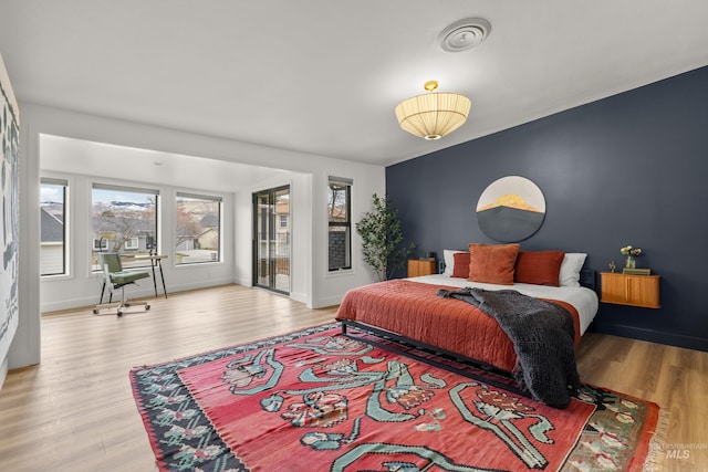 bedroom featuring visible vents, access to outside, wood finished floors, and baseboards