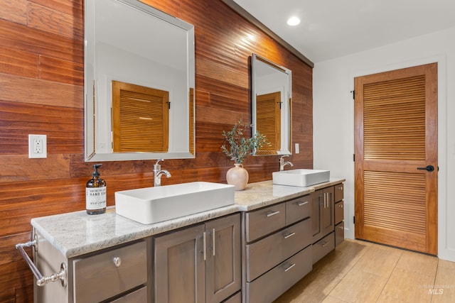 full bathroom with wood walls, a sink, recessed lighting, and double vanity